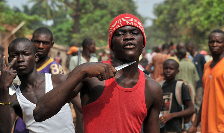 A man holds a knife to his throat claiming that he is looking for Muslims to cut off their heads in Bangui. Photo: AFP