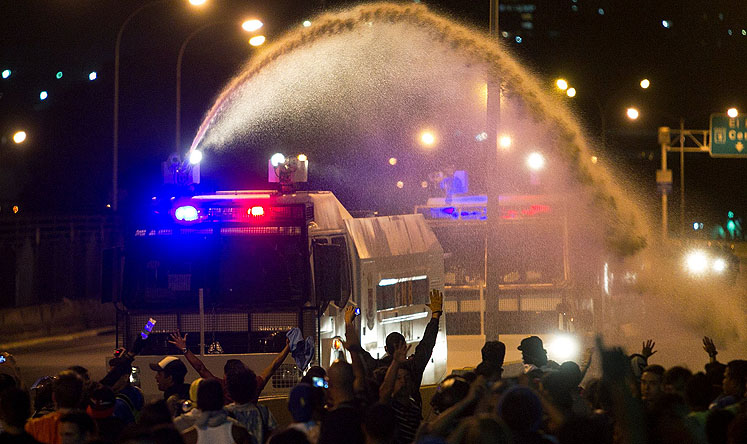 A police water canon sprays demonstrators during protests in Caracas on Friday. Photo: AP