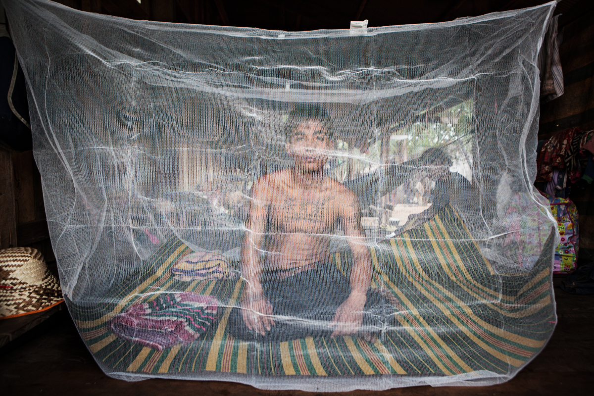 A villager sits beneath a mosquito net in Cambodia’s Pailin province, which is ground zero for drug-resistant strains of malaria.