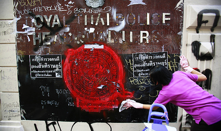 An anti-government protester volunteers to clean graffiti debris from the main gate of the Royal Thai Police Headquarters in Bangkok on Saturday. Photo: Reuters