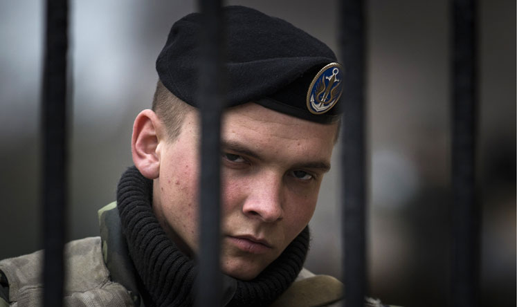 A Ukrainian soldier guards a gate of a naval base of the Ukrainian military in Kerch. Photo: Reuters 
