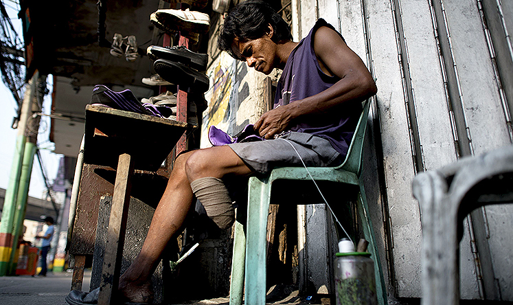 Shoe repair worker Alberto Tiong earns US$6 a day from his Manila street stall. Photo: AFP