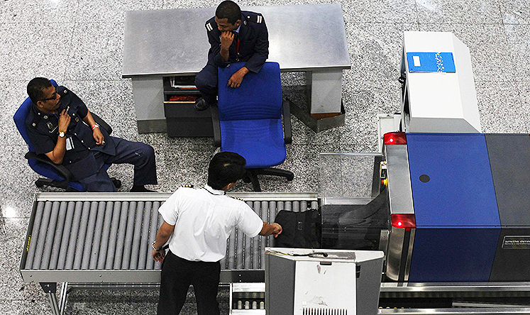 Airport security personnel chat as a pilot has his bag screened at the departure hall of the Kuala Lumpur International Airport in Sepang. Photo: Reuters