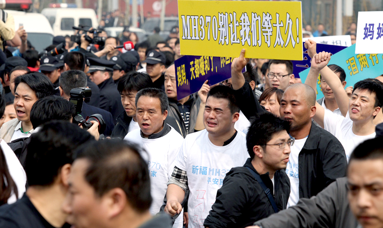 Family members of MH370 passengers hold up placards in a protest outside the Malaysian embassy in Beijing on March 25. Photo: SCMP/Simon Song