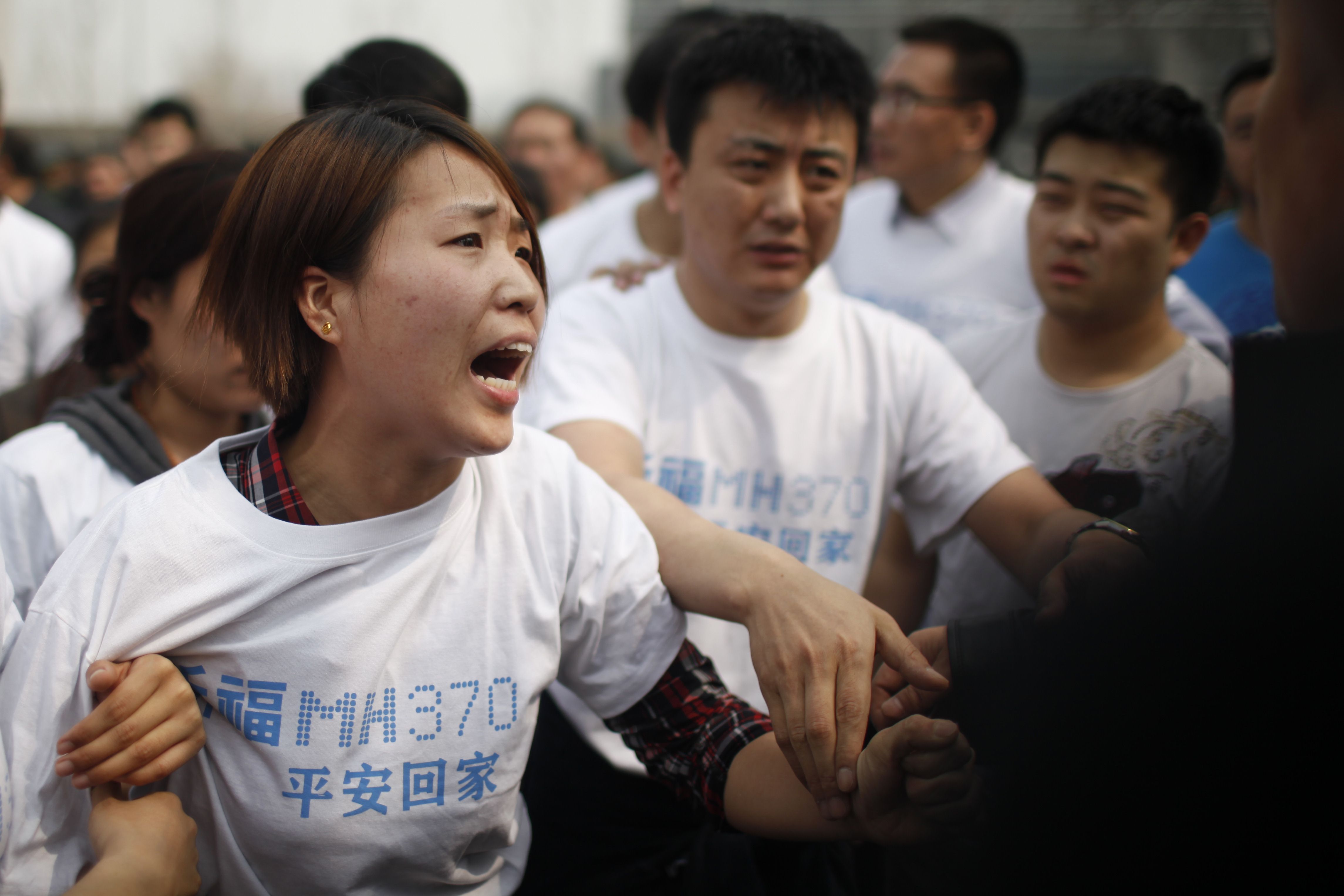 A relative of passengers on missing Malaysia Airlines flight MH370 yells at a security personnel during  a protest outside the Malaysian embassy in Beijing on Tuesday.