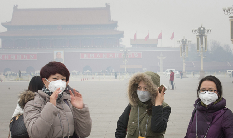 Tourists wearing face masks to protect themselves from thick smog outisde the Great Hall of the People in Beijing earlier this month. Photo: EPA