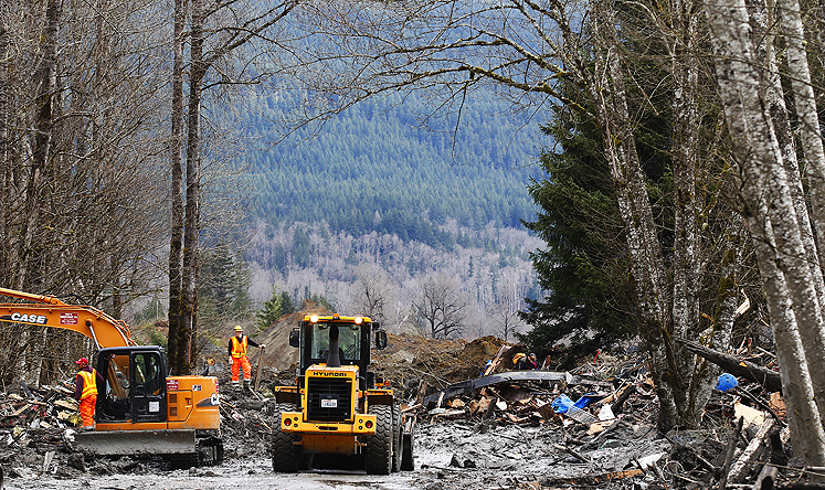 Heavy equipment moving debris from site of the mudslide on Wednesday. Photo: AP