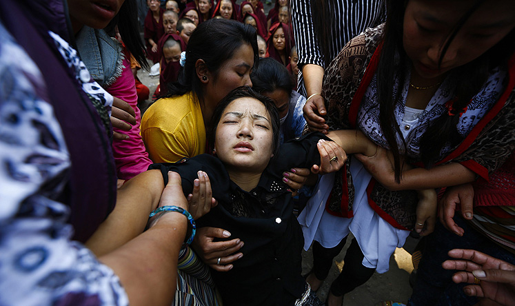 The daughter of Ang Kaji Sherpa, one of the victims of the Mount Everest avalanche, collapses during his cremation ceremony. Photo: EPA