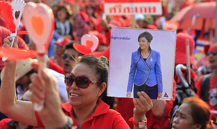 A Thai pro-government Red Shirt protester holds a placard showing a picture of caretaker Thai Premier Yingluck Shinawatra (R) during a rally on the outskirts of Bangkok earlier this month. Photo: EPA
