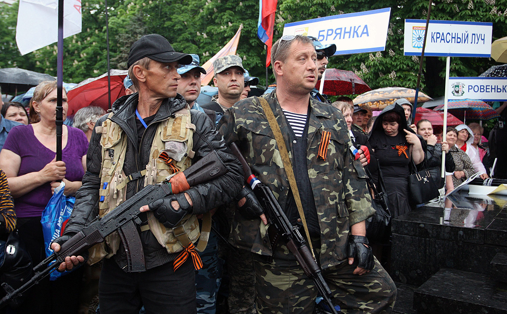 Armed pro-Russian men stand guard as Valery Bolotov (centre), self-declared governor Lugansk, delivers a message during the announcement of referendum results. Photo: EPA