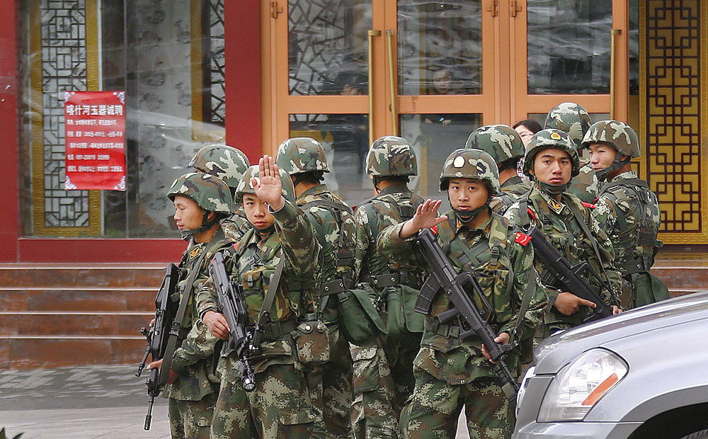 Paramilitary policemen gesture to stop a photographer from taking pictures as they stand guard after explosives attack hit downtown Urumqi on Thursday. Photo: Reuters