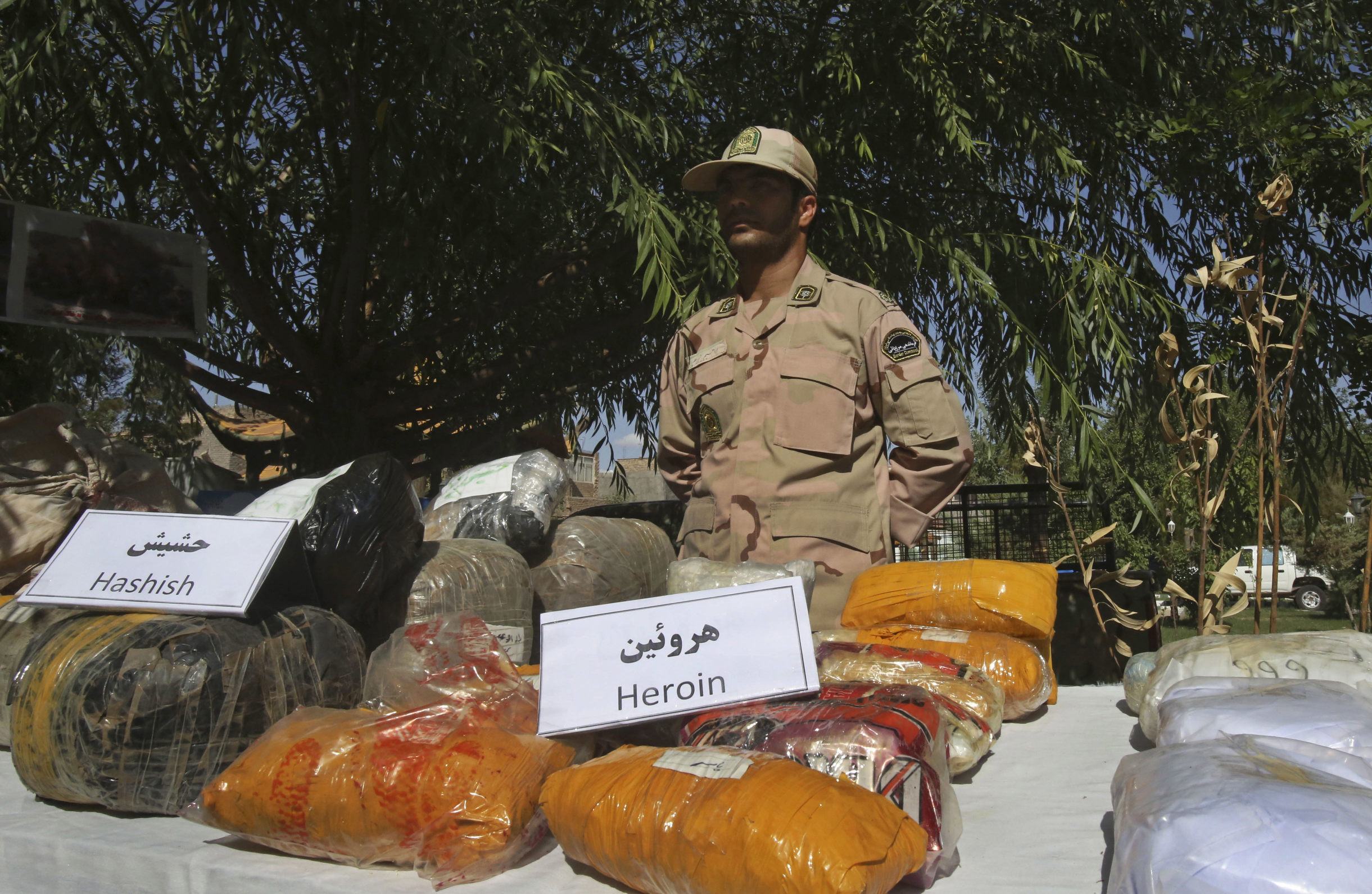 An Iranian police officer stands behind drugs seized from smugglers at a border post in Taibad on the border with Afghanistan. Photo: AP