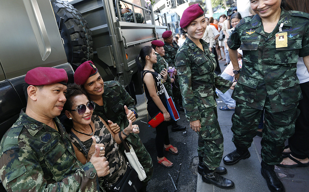 A Thai civilian poses with soldiers during the 'Returning happiness to the people' event near the Victory Monument in Bangkok on Wednesday. Photo: EPA