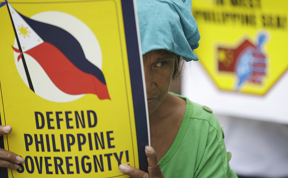 A protester displays a placard during a rally in front of the Chinese Consulate at the financial district of Makati city, east of Manila, Philippines on Friday May 16. photo: AP