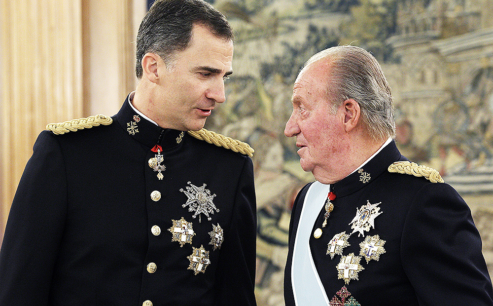 Spain's King Juan Carlos, right, talks to his son the Spain's newly crowned King Felipe VI after handing over his military chief sash to him during a ceremony at the Zarzuela Palace in Madrid. Photo: AP