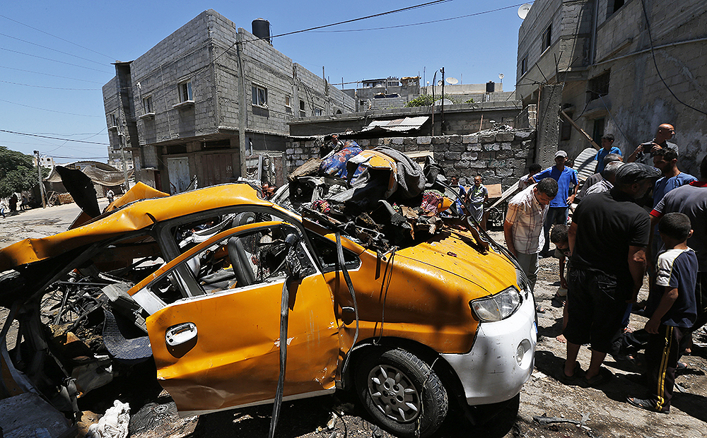 Palestinians gather around a vehicle that was destroyed by an Israeli missile strike in Khan Younis, southern Gaza Strip. Photo: AP