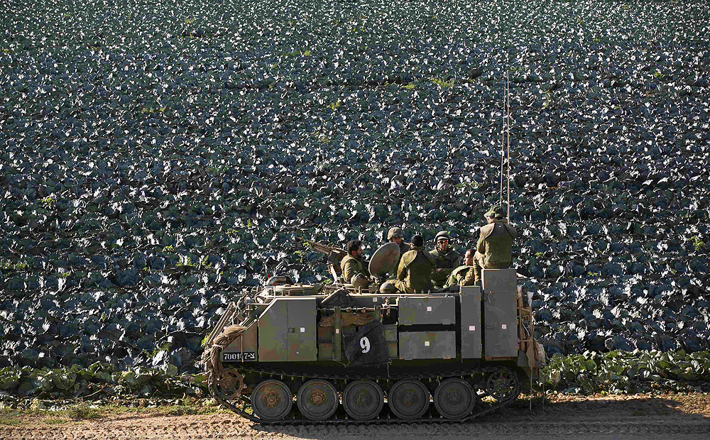 Israeli soldiers ride in an armoured personnel carrier next to a cabbage field near the Gaza Strip. Photo: Reuters
