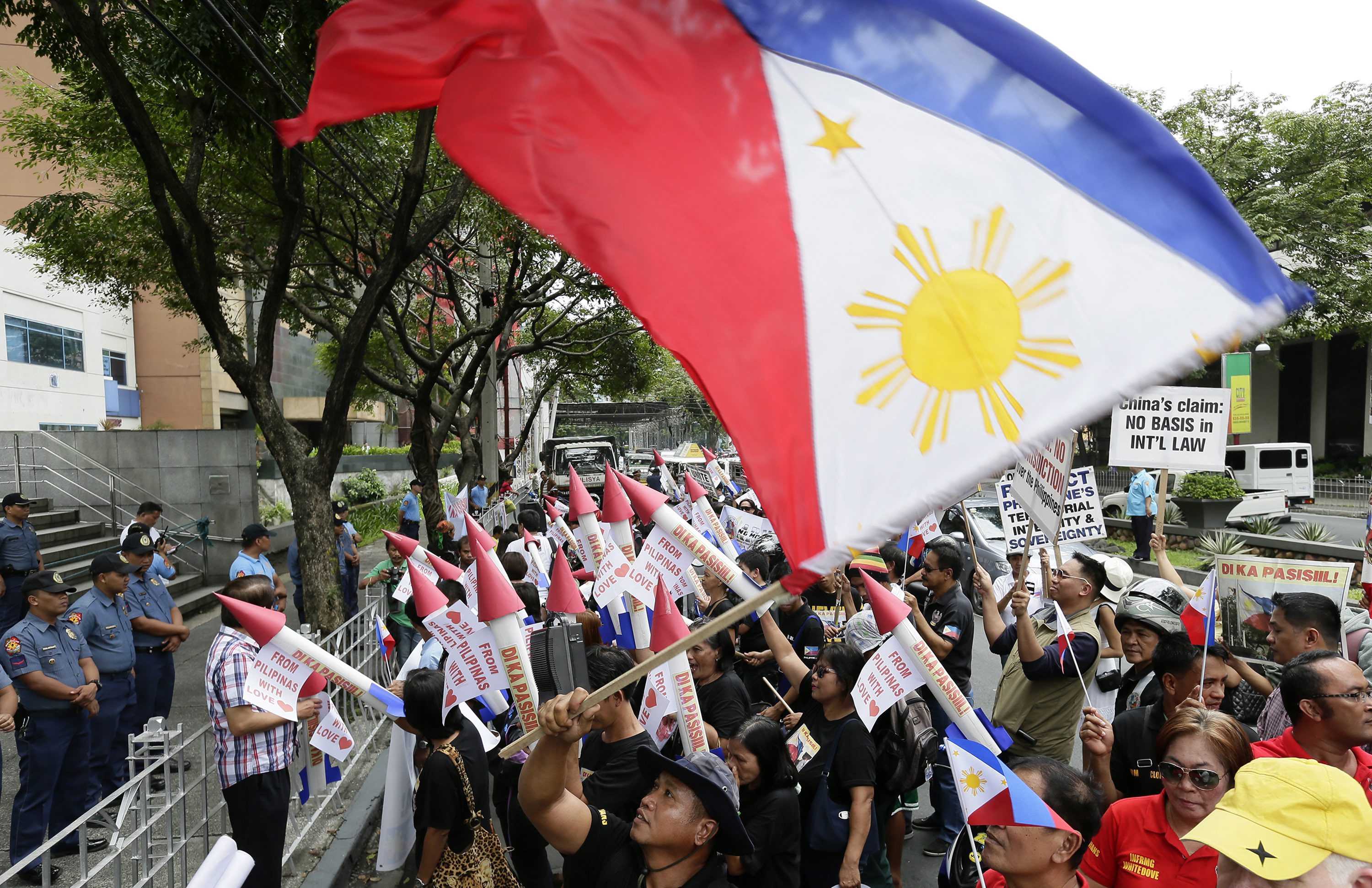 A Filipino activist waves a national flag while women brandish mock missiles as they shout anti-China slogans as part of a protest against Chinese aggression in Manila's financial district on Thursday. Photo: EPA