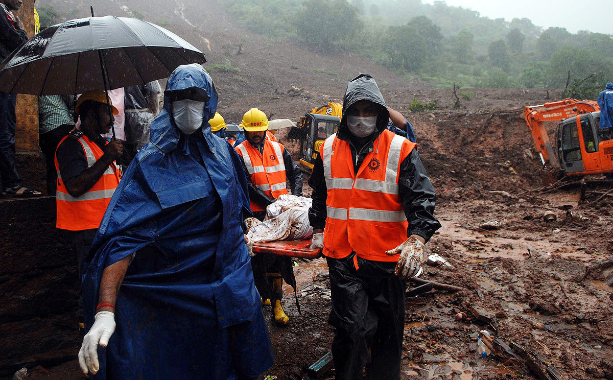 Workers from the National Disaster Management Force carry a body during a rescue operation after a landslide in Malin village, India on Thursday. Photo: Xinhua