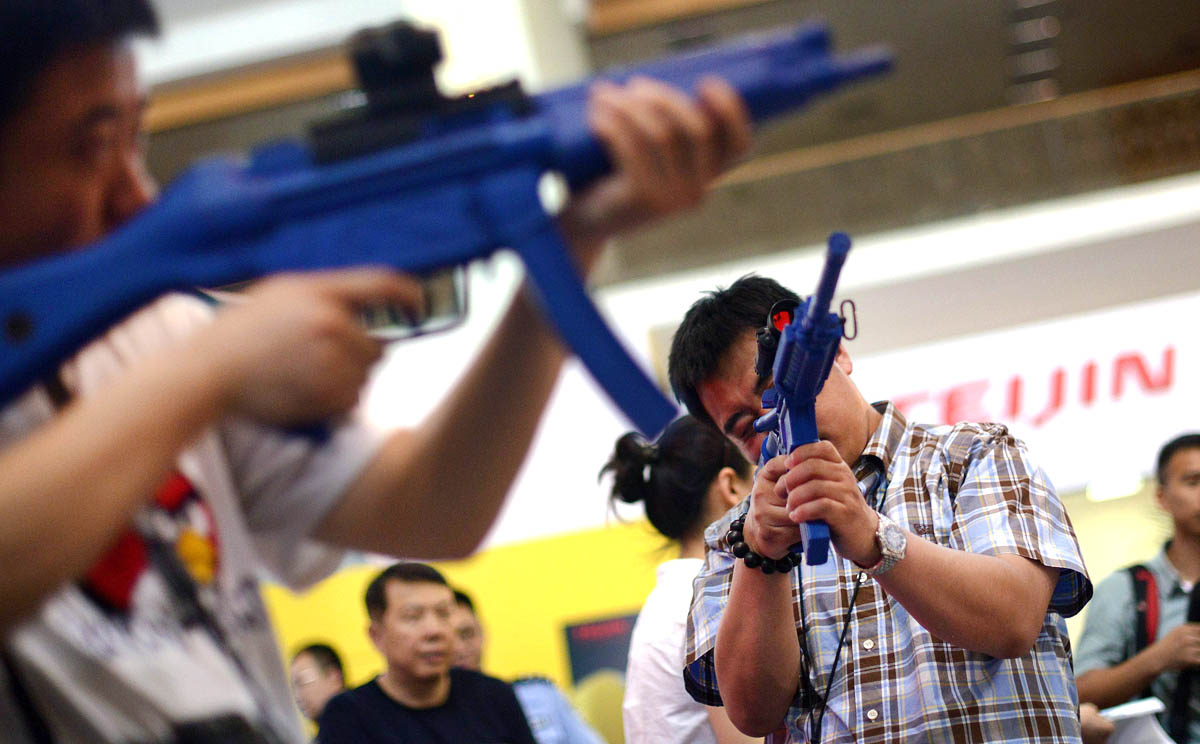 Visitors hold gun models at a rare firearms exhibition in China. Photo: AFP
