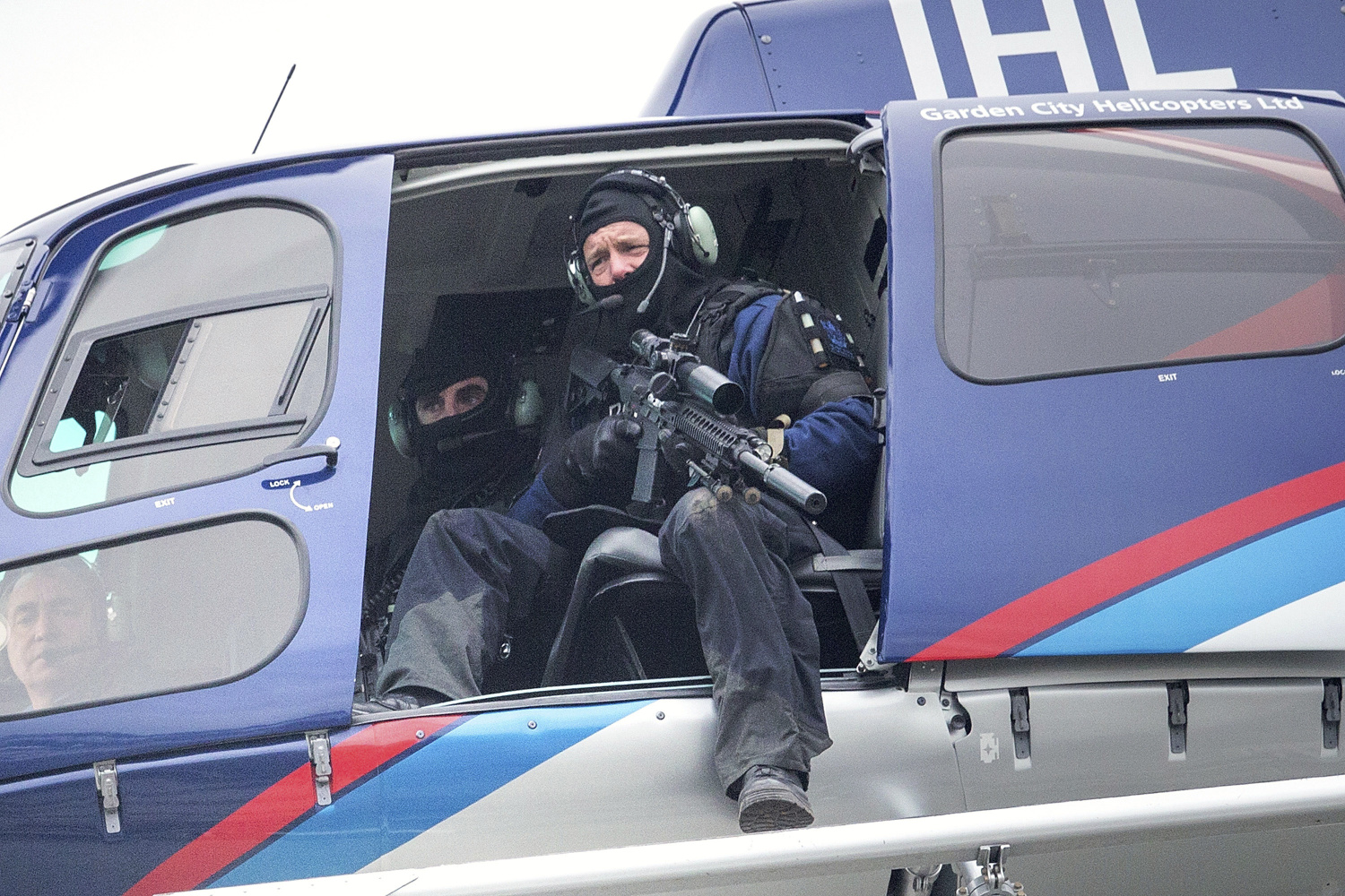 A police officer with a high powered weapon searches for the suspect from a helicopter in Ashburton, New Zealand, earlier today. Photo: AP