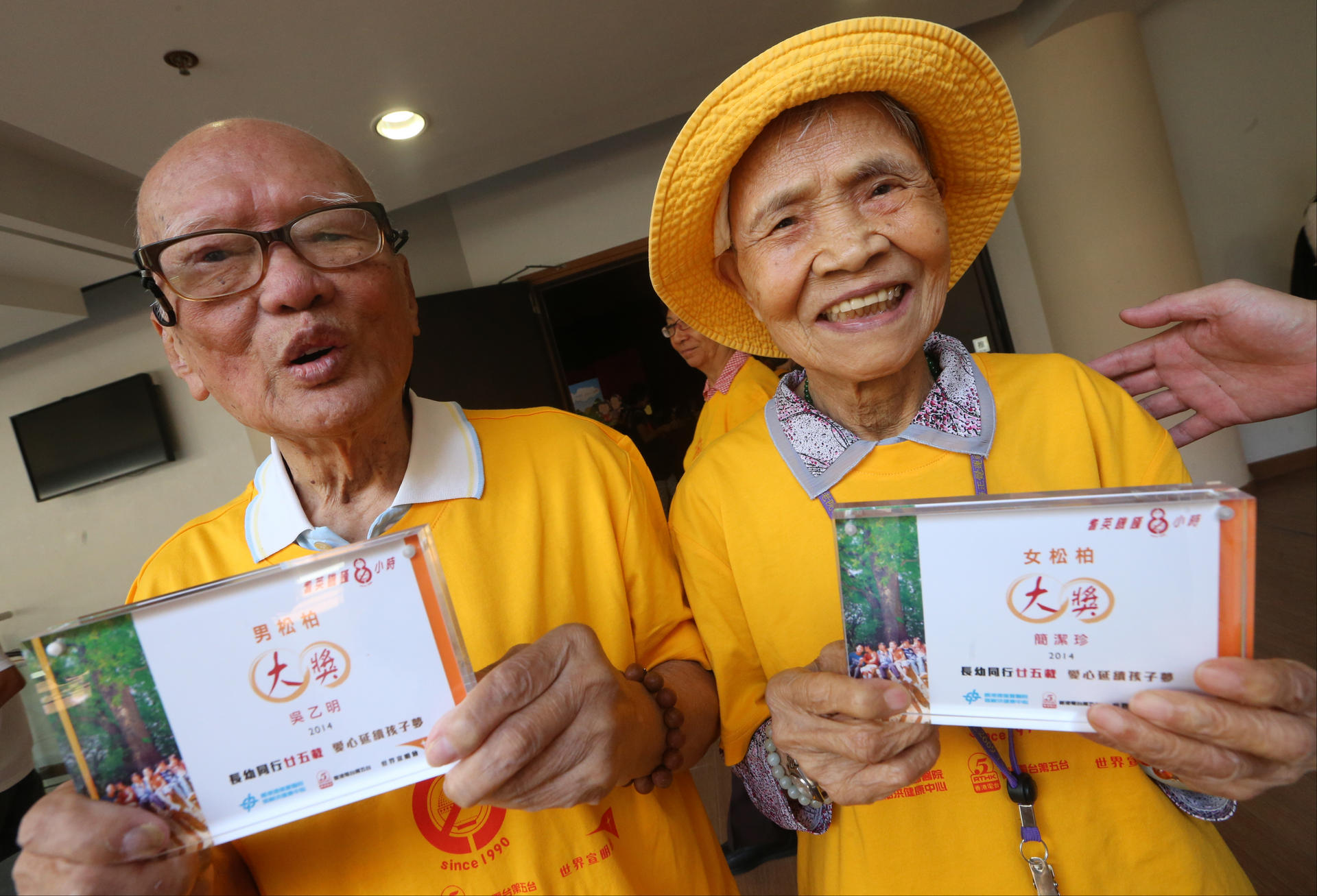 Ng Yuet-ming, 101, and Kan Kit-chun, 98, smile through their hunger yesterday at Sha Tin's Heung Yee Kuk building. Photo: David Wong