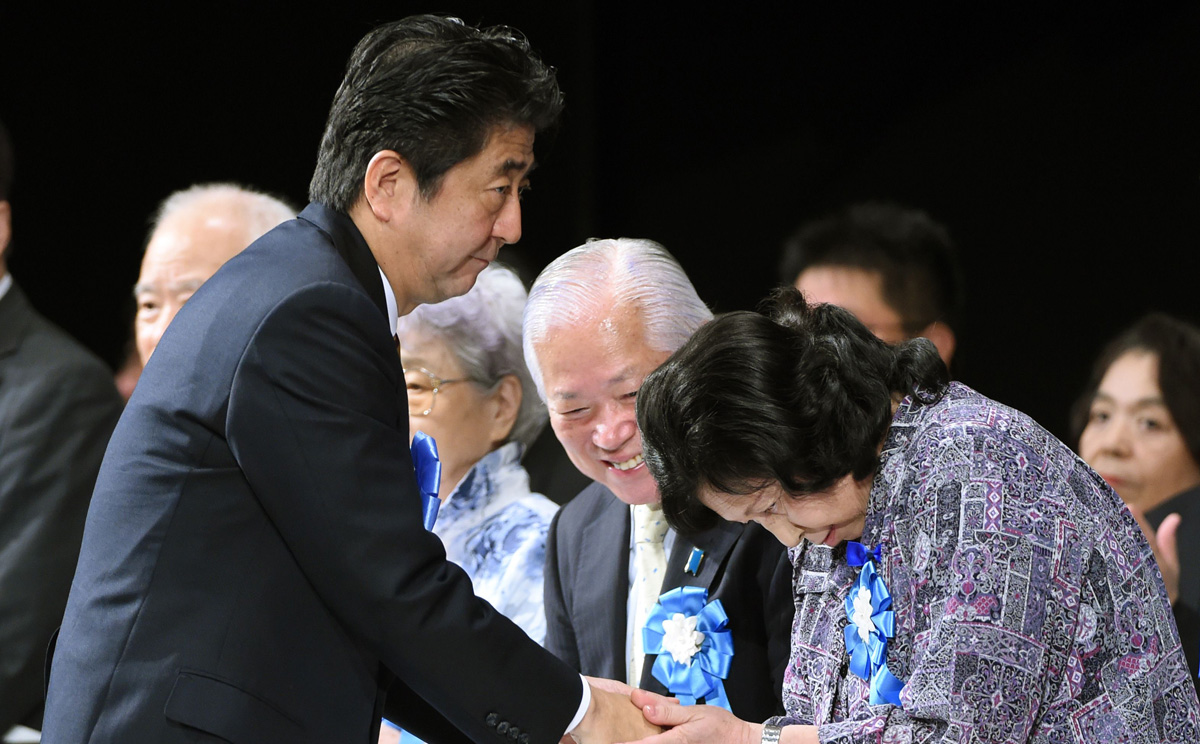 Japanese Prime Minister Shinzo Abe shakes hands with abduction victim Hitomi Soga (right) on Saturday in Tokyo at a rally to support families of abduction victims by North Korea. Photo: AFP