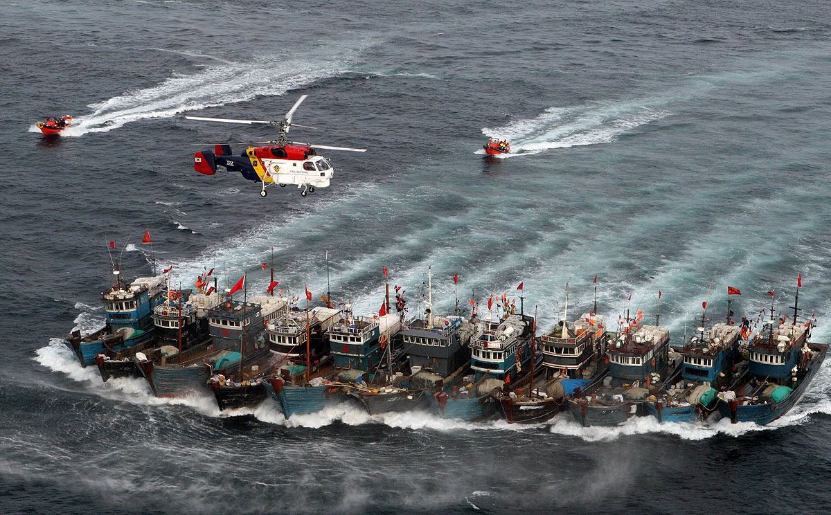 File picture from November 2011 shows Chinese fishing boats bound together with ropes chased by a South Korean coastguard helicopter and rubber boats packed with commandos, after alleged illegal fishing in the Yellow Sea. Photo: AFP
