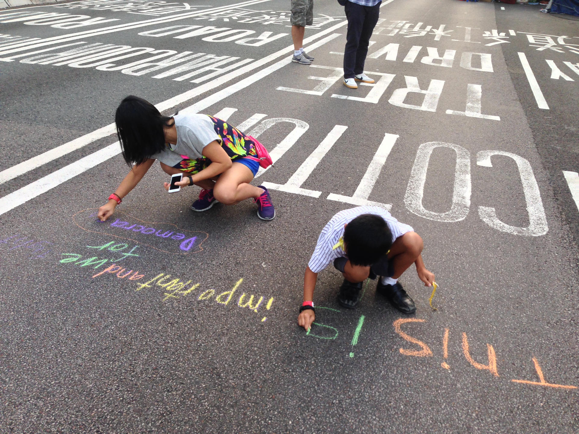 Students involved in a mobile democracy class write with chalk on the road during the Occupy protests.