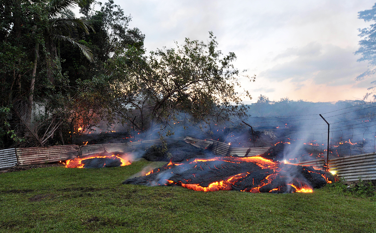 Burning lava pushes through a fence marking a property boundary above Pahoa in Hawaii. Photo: AFP