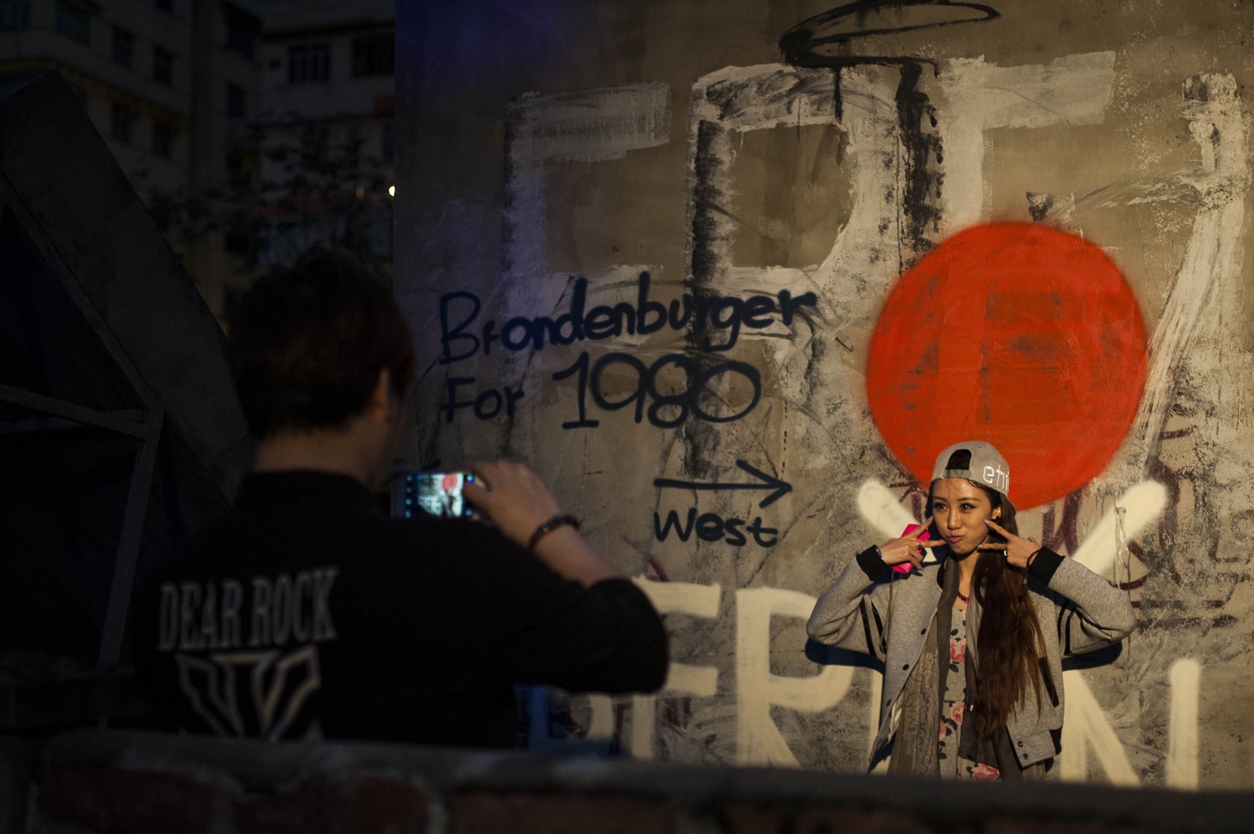 Visitors take pictures in front of a Berlin Wall graffiti replica at the Berlin Fest at Cattle Depot Artist Village in Hong Kong, to commemorate the 25th anniversary of the fall of the wall. Photo: AFP