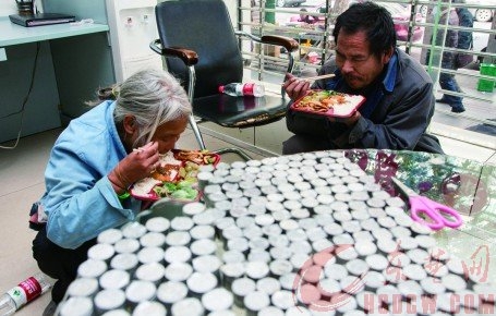 Wang Fang and her husband, Gao Guanglin, enjoy lunch at 
the China Postal Savings Bank in Huangshi as the coins they collected sit on the table. Photo: SCMP Pictures


