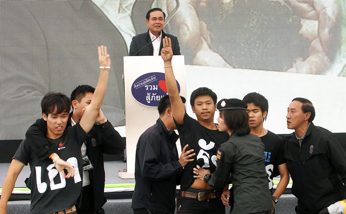 Thai student activists raise the three-fingered salute in front of Thai Prime Minister Prayuth Chan-ocha as he speaks in Khon Kaen, northeast of Bangkok. Photo: AP