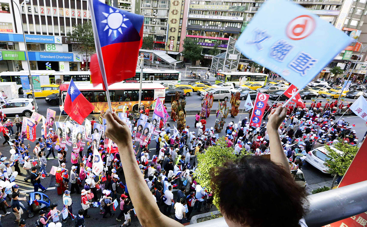A Nationalist Party supporter waves a Taiwan flag and a banner in support of one of the Taipei mayoral candidates, KMT's  Sean Lien, during an campaign rally last weekend. Photo: Reuters
