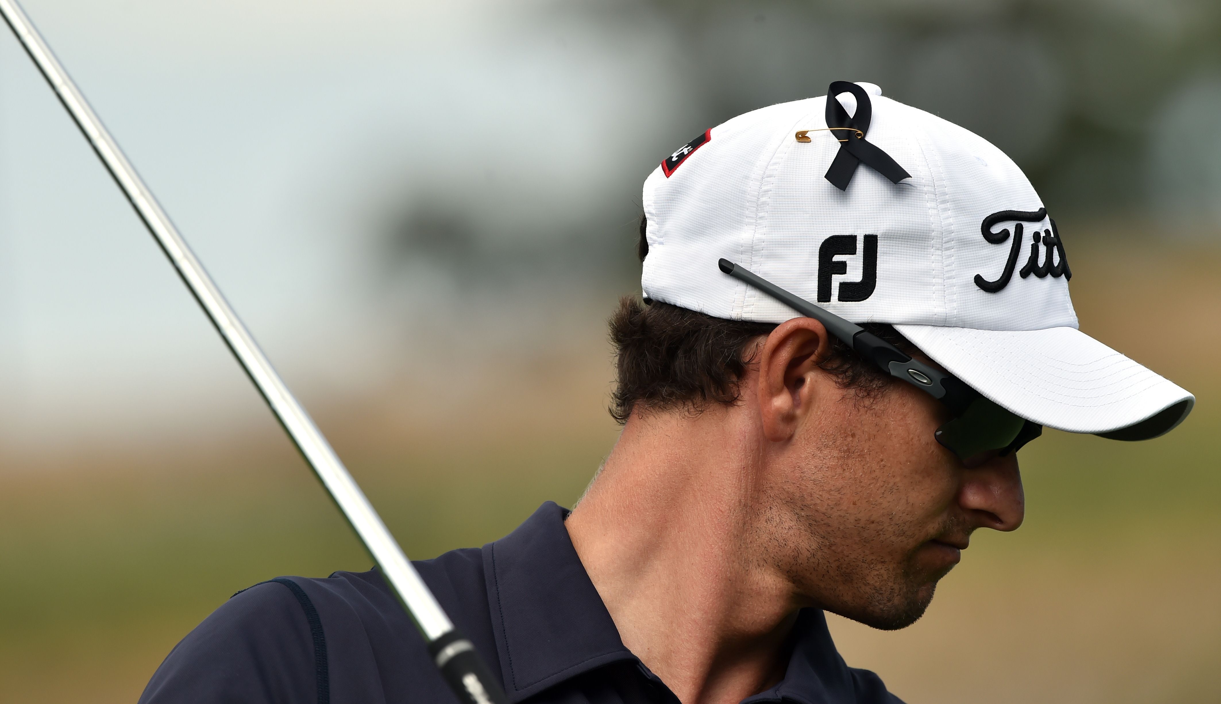Adam Scott of Australia wears a black ribbon on his cap in memory of Australian cricketer Phillip Hughes on the second day of the Australian Open. Photo: AFP