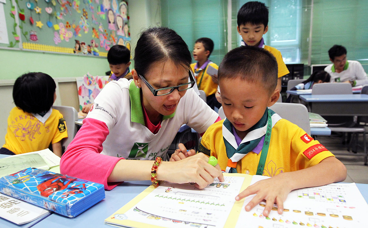 Hang Seng team volunteer Kitty Lai Man-ying helps primary school pupil Lee kit-ho. Photo: Edward Wong