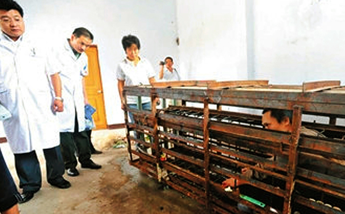 Doctors view the cage Wang Dafeng had been kept in. Photo: The Beijing News