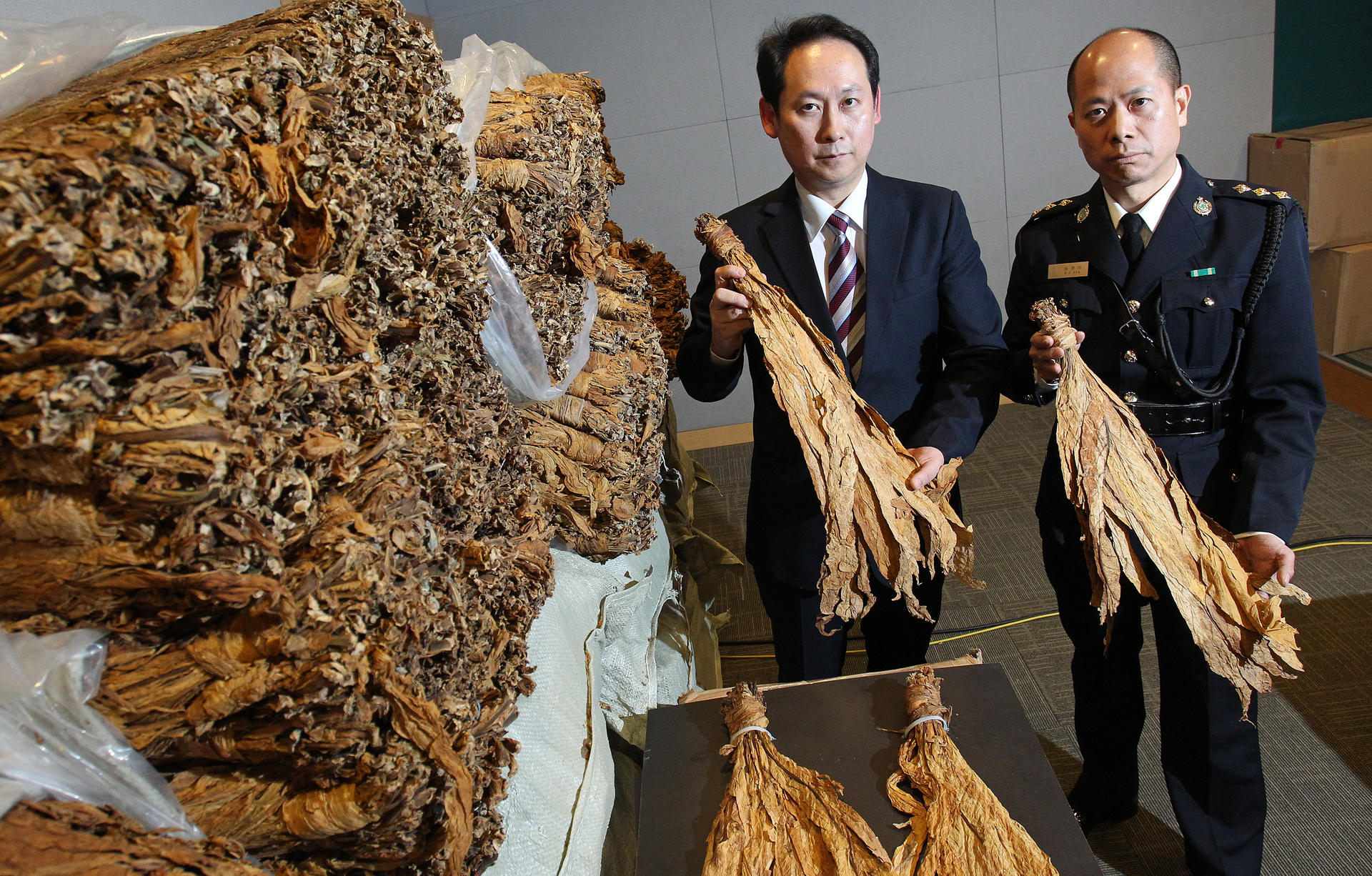 Customs officers Simon Wan (left) and Tse Pok-chung show off some of the massive haul of seized tobacco. Photo: May Tse