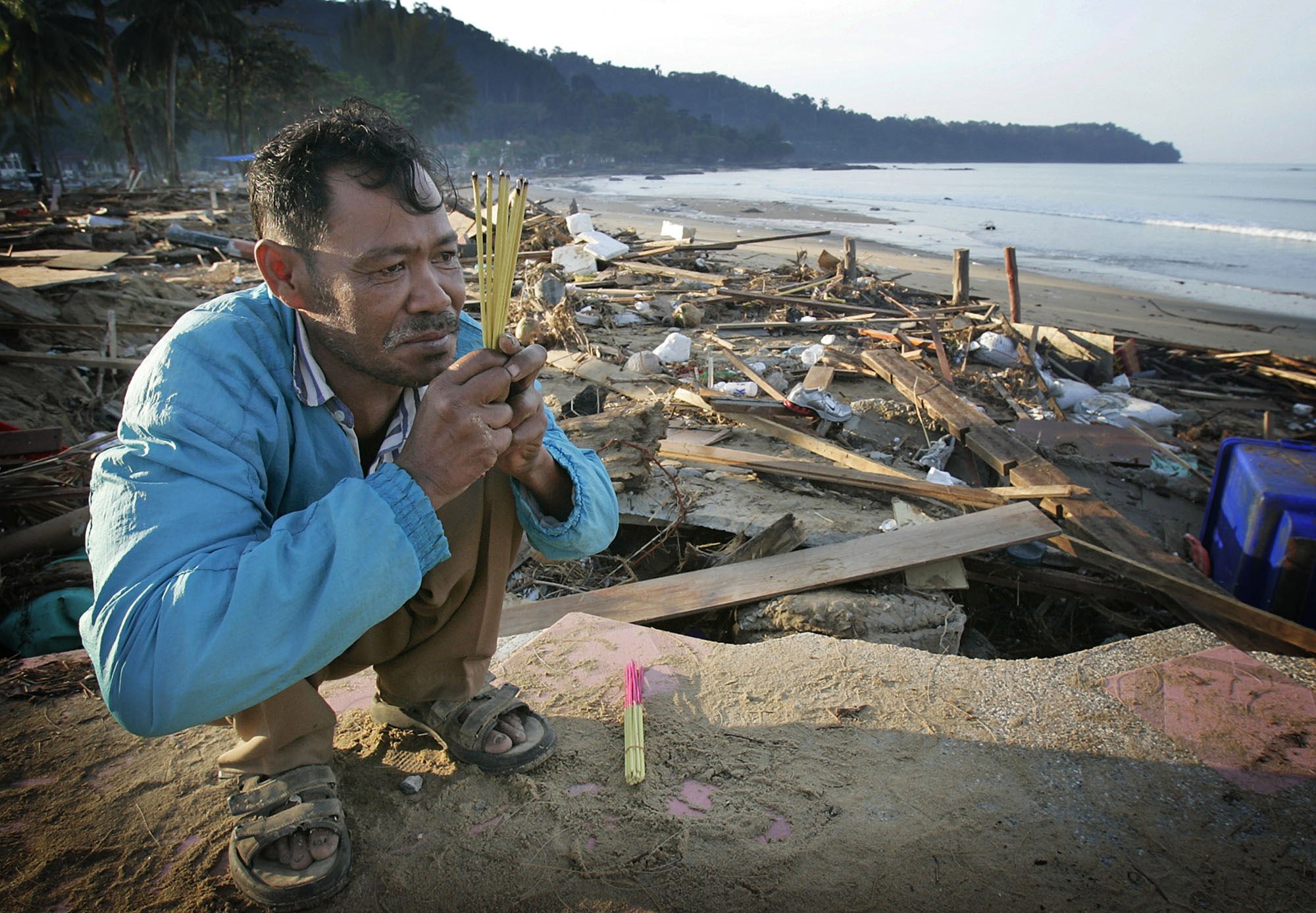 In this photo taken near Khao Lak, Thailand, on December 29, 2004, a man offered prayers for his sister who was swept out to sea. Photo: AP 