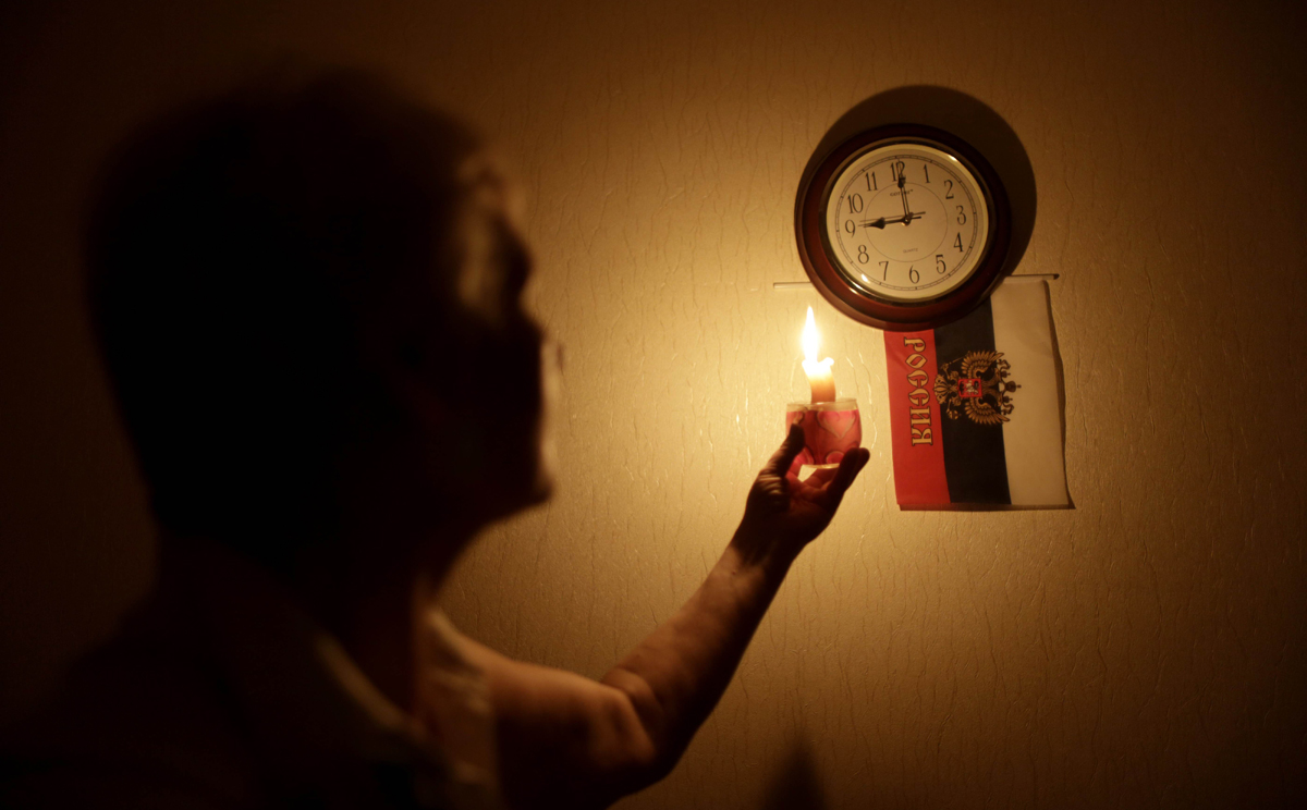 A woman uses a candle to illuminate a clock during a power outage in Simferopol, Crimea on Friday. Photo: AFP 
