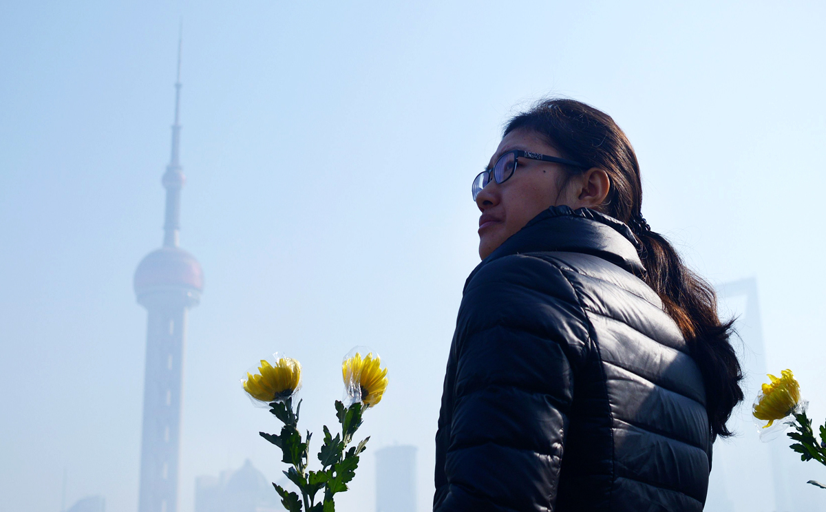A woman holds a flower bouquet as she prepares to pray for victims of the New Year's stampede in Shanghai. Photo: AFP