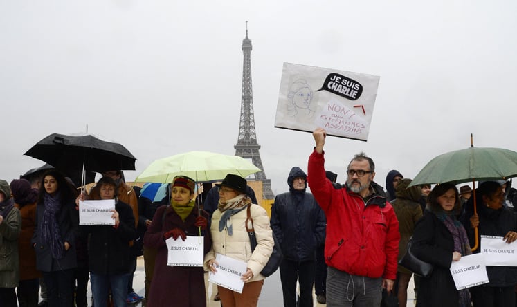 A man holds a sign reading "Je suis Charlie" (I am Charlie) as people observe a minute of silence in front of the Eiffel Tower in Paris. Photo: AFP