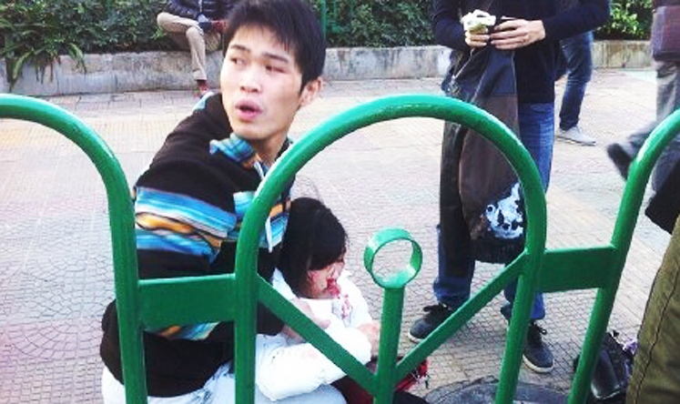 A man attends to an injured woman after this morning's fire on a bus in Xiamen, Fujian province, during rush hour. Photo: Sina Xiamen