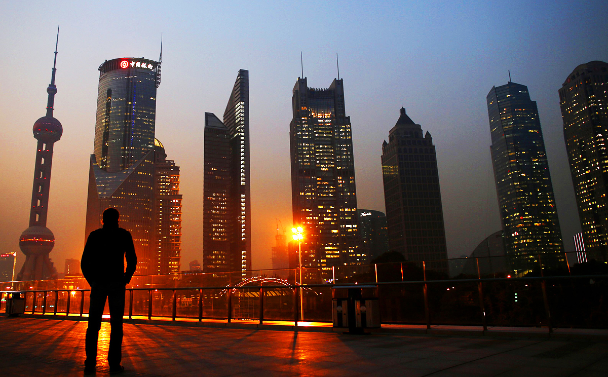A man looks at the Pudong financial district of Shanghai. China's full-year 2014 GDP grew at its slowest pace in 24 years. Photo: Reuters