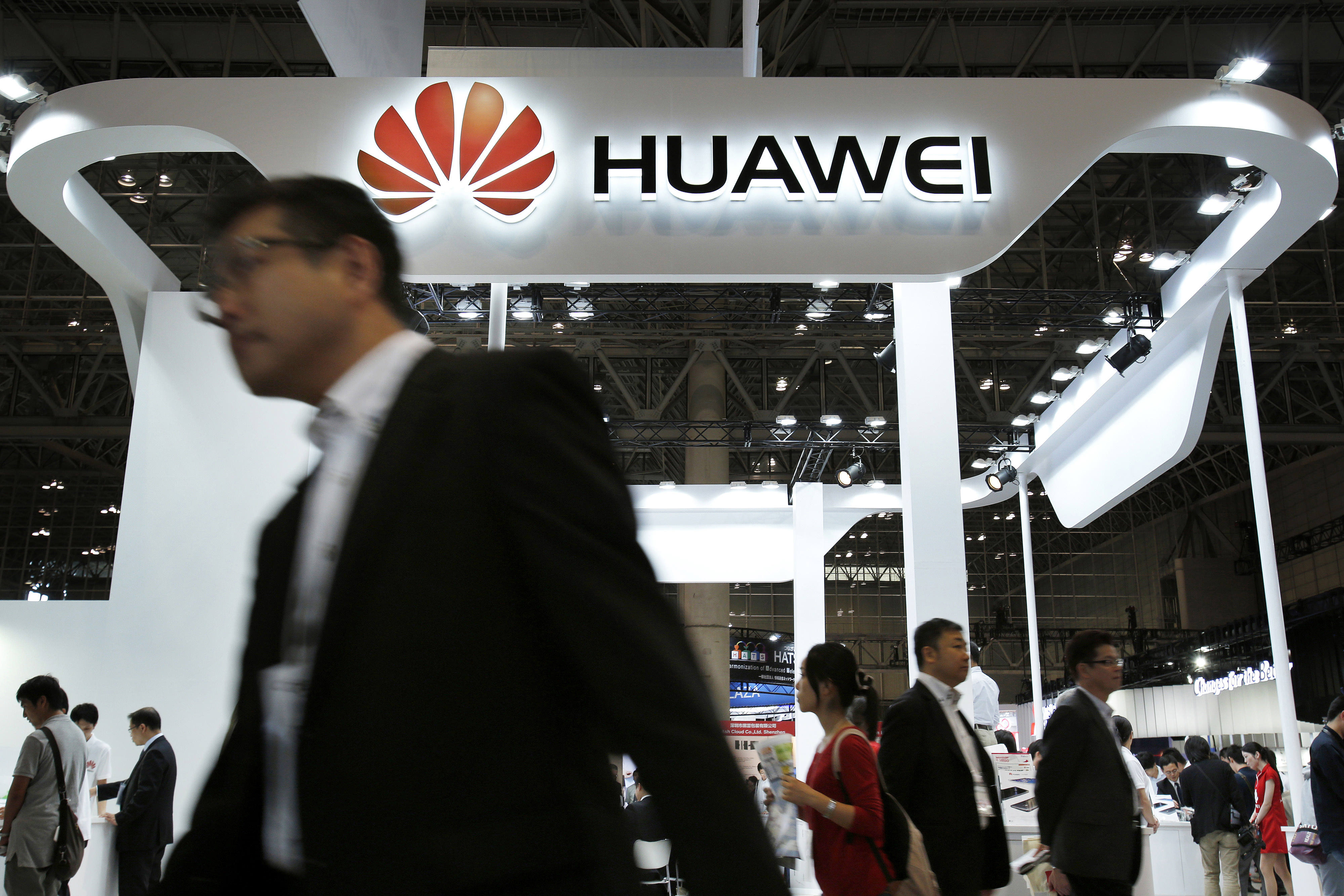 People walk past a booth of Huawei, which plans to increase smartphone shipments to 100 million units in 2015. Photo: Bloomberg 
