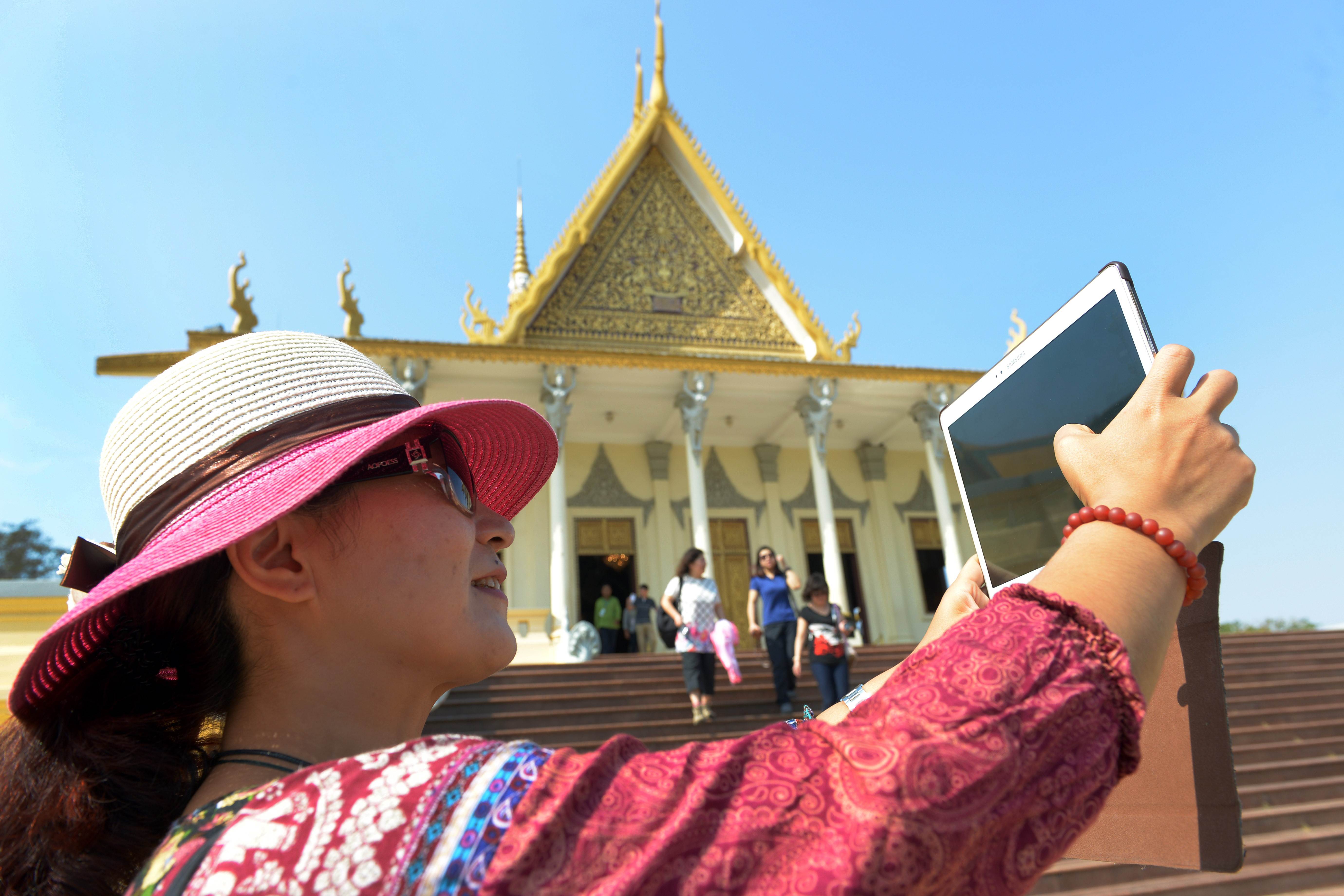 A Chinese tourist takes a photo with her tablet at the Royal Palace in Cambodia. Photo: AFP