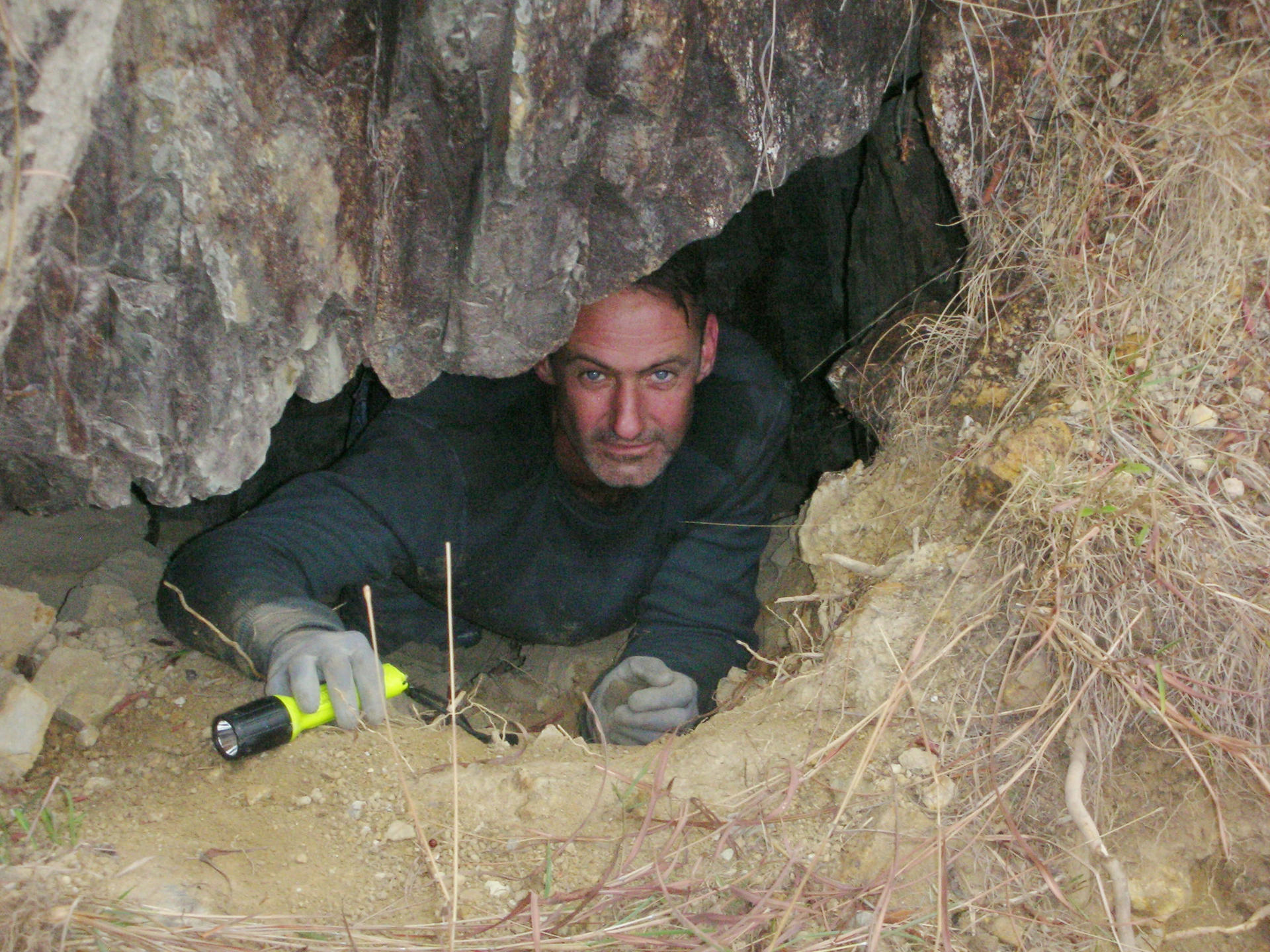 David Willott searching for relics in a cave. Photo: Red Door News