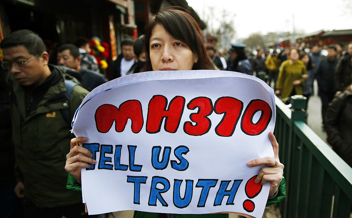 Catherine Gang, whose husband Li Zhi was onboard the missing Malaysia Airlines flight MH370, holds a banner in Beijing. Photo: Reuters
