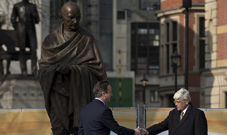 British PM David Cameron and Gandhi's grandson Gopalkrishna Gandhi (right) shake hands beneath the new statue of Mahatma Gandhi in Parliament Square, London on Saturday. Photo: AP