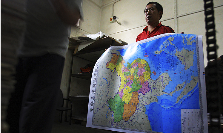 A print worker holds an officially-approved map of China that includes the areas Beijing claims in the South China Sea in this file picture from June 2014. Photo: AP